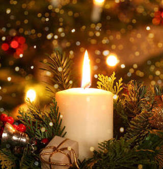 burning advent candle Christmas decoration with flare lights in front of a Christmas tree